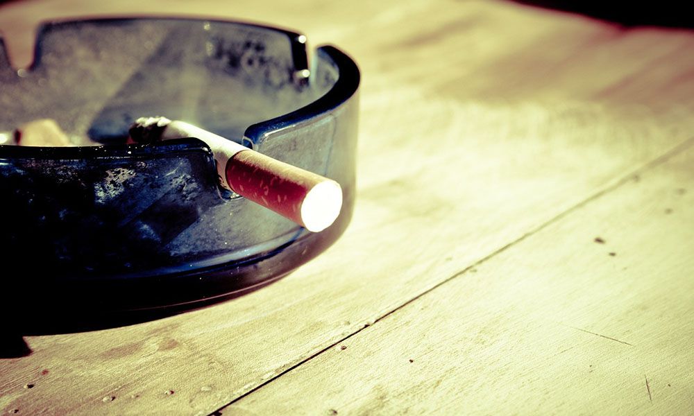 Cigarette in an ashtray on a wooden table