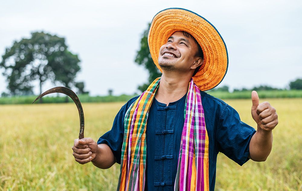 Farmer wearing straw hat and holding sickle in hand