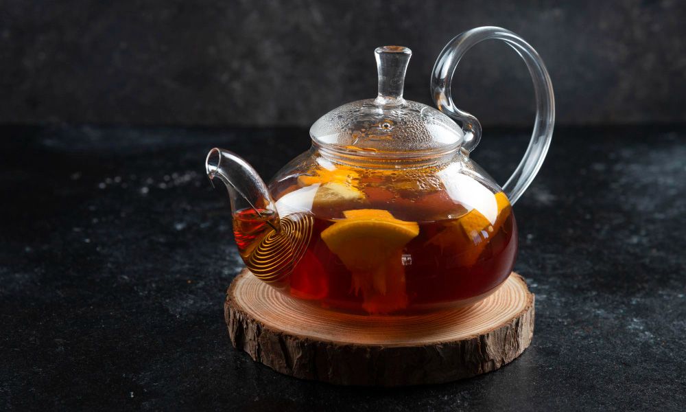 Glass teapot with hot tea and lemon slices