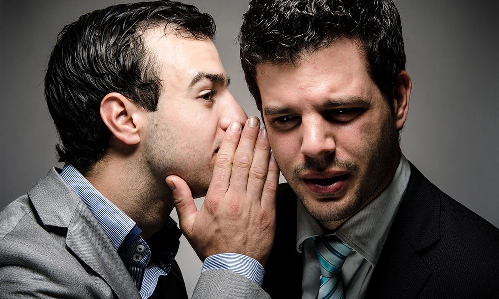 Man whispering something in anothers ear