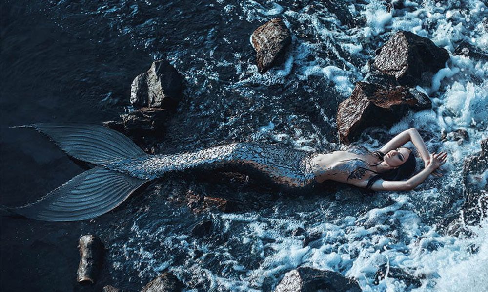 Mermaid lying on the rocky beach