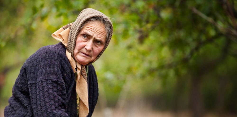 Old woman standing in the background of an orchard