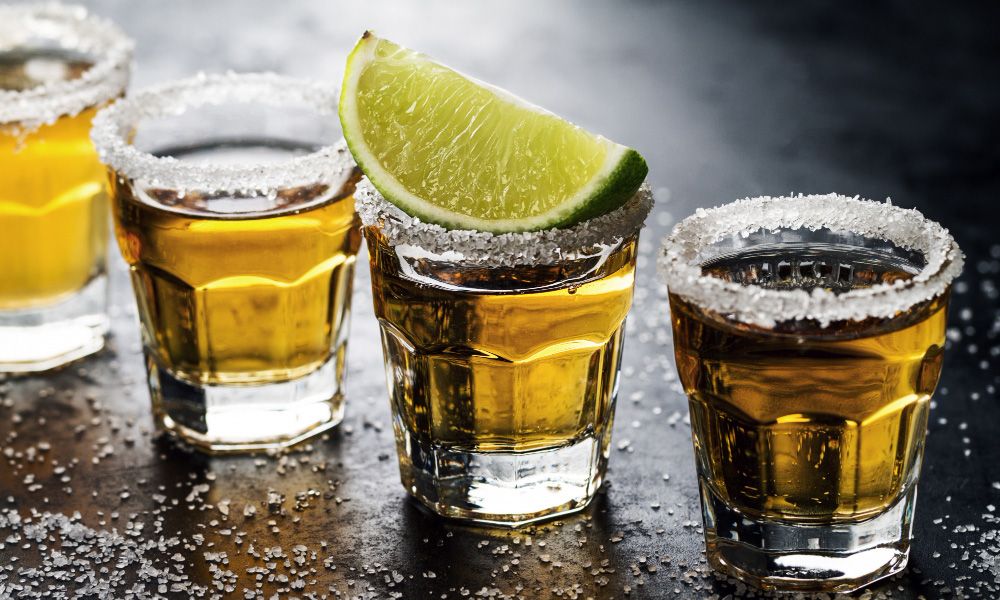 Row of tequila shots on a dark background