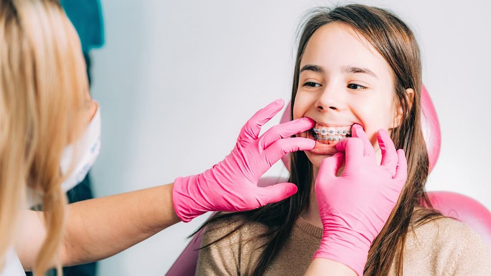 The orthodontist checks the braces on the patients teeth