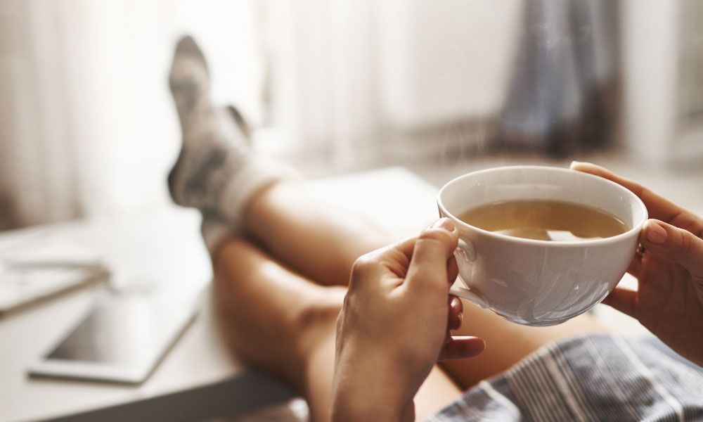 Woman keeping legs on the table while drinking coffee