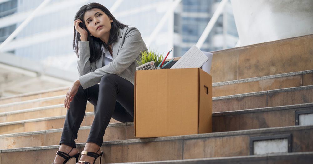 Woman sitting on stairs next to a cardboard with things from work